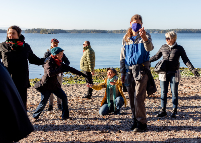 Henkilöitä syksyilessä, aurinkoisella rannalla luovassa muodostelmassa.