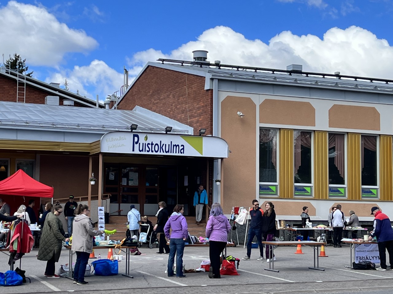 Puistokulma-talon parkkipaikalla on ihmisiä kirpputorilla.