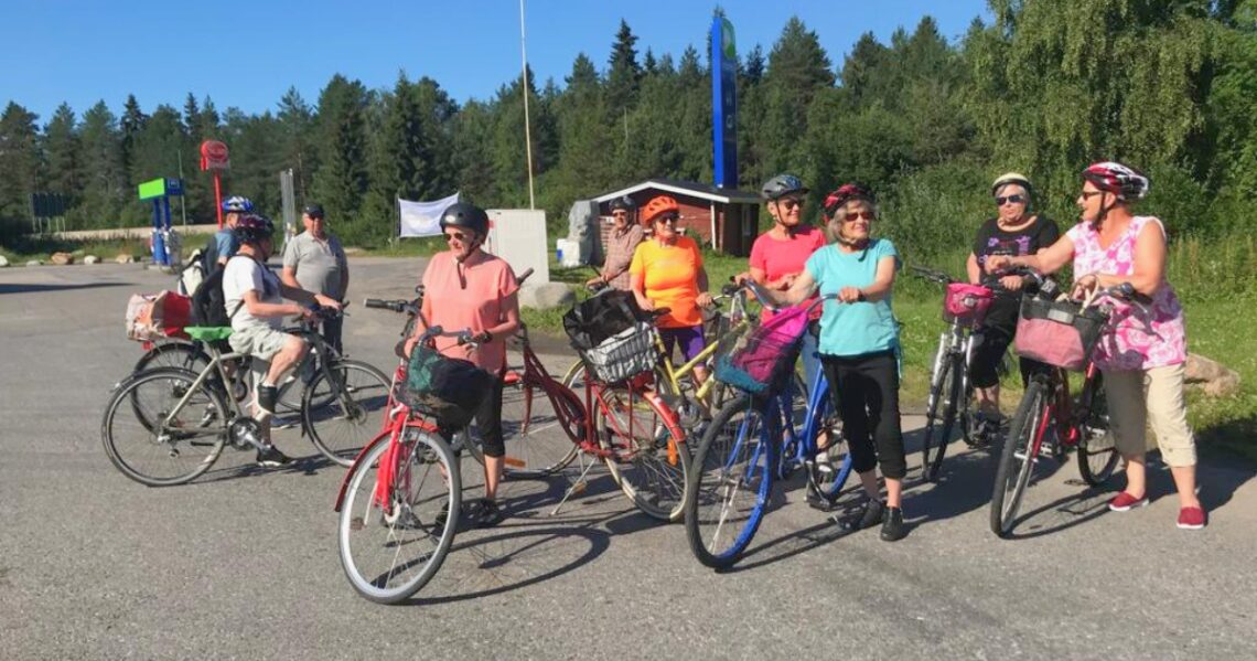 Ryhmä eläkeläisiä pyörineen metsän laidalla.