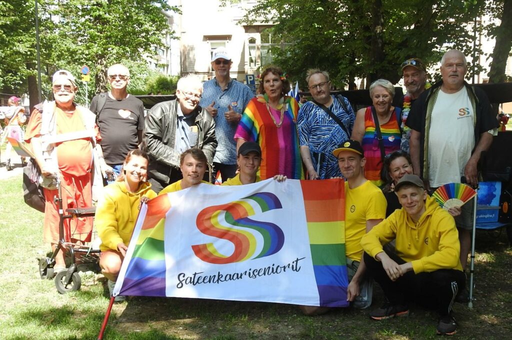 Ryhmäkuva sateenkaarisenioreista puistossa.