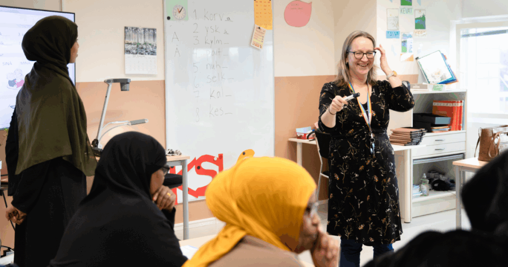 Opettaja keskustelee luokkahuoneessa oppijoiden kanssa.